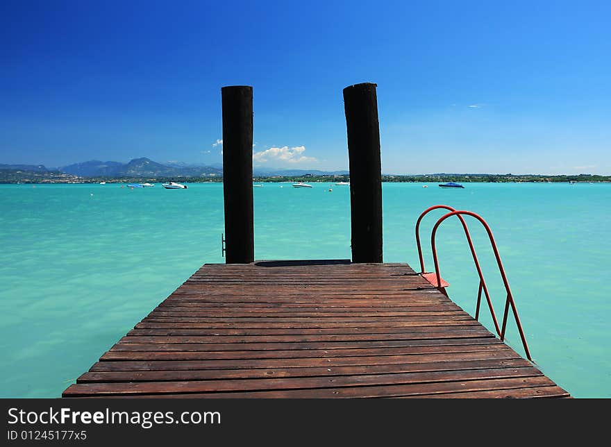 A small jetty in lake Garda Italy, fantastic color in the water and sky. Perfect for concepts of vacation or holidays