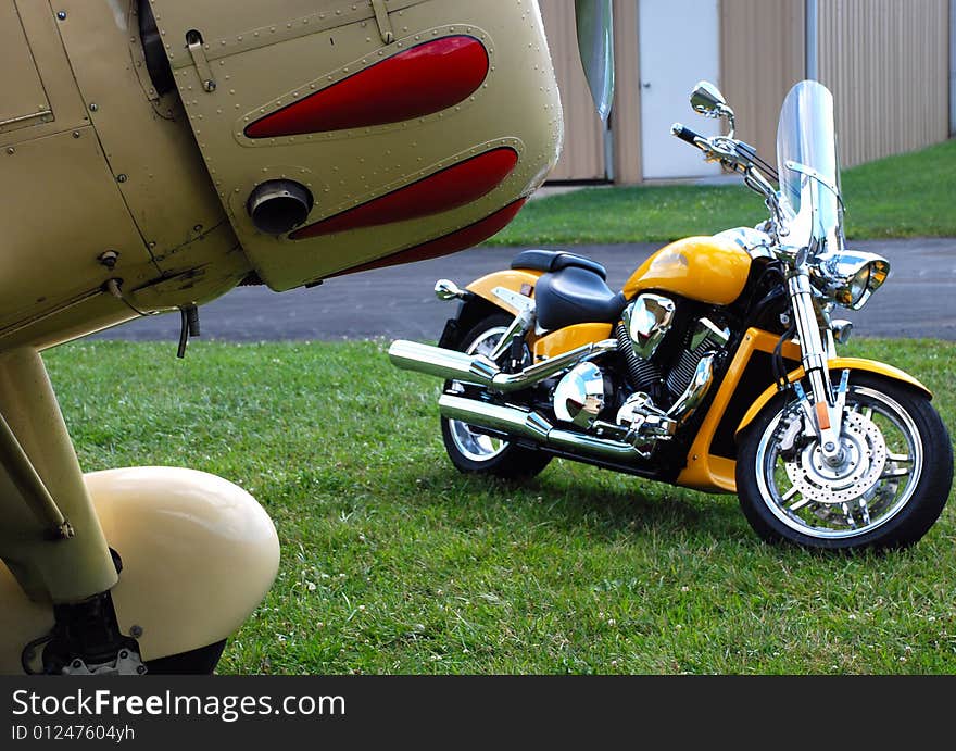 This is a shot of a custom motorcycle and front of an antique aircraft. This is a shot of a custom motorcycle and front of an antique aircraft.