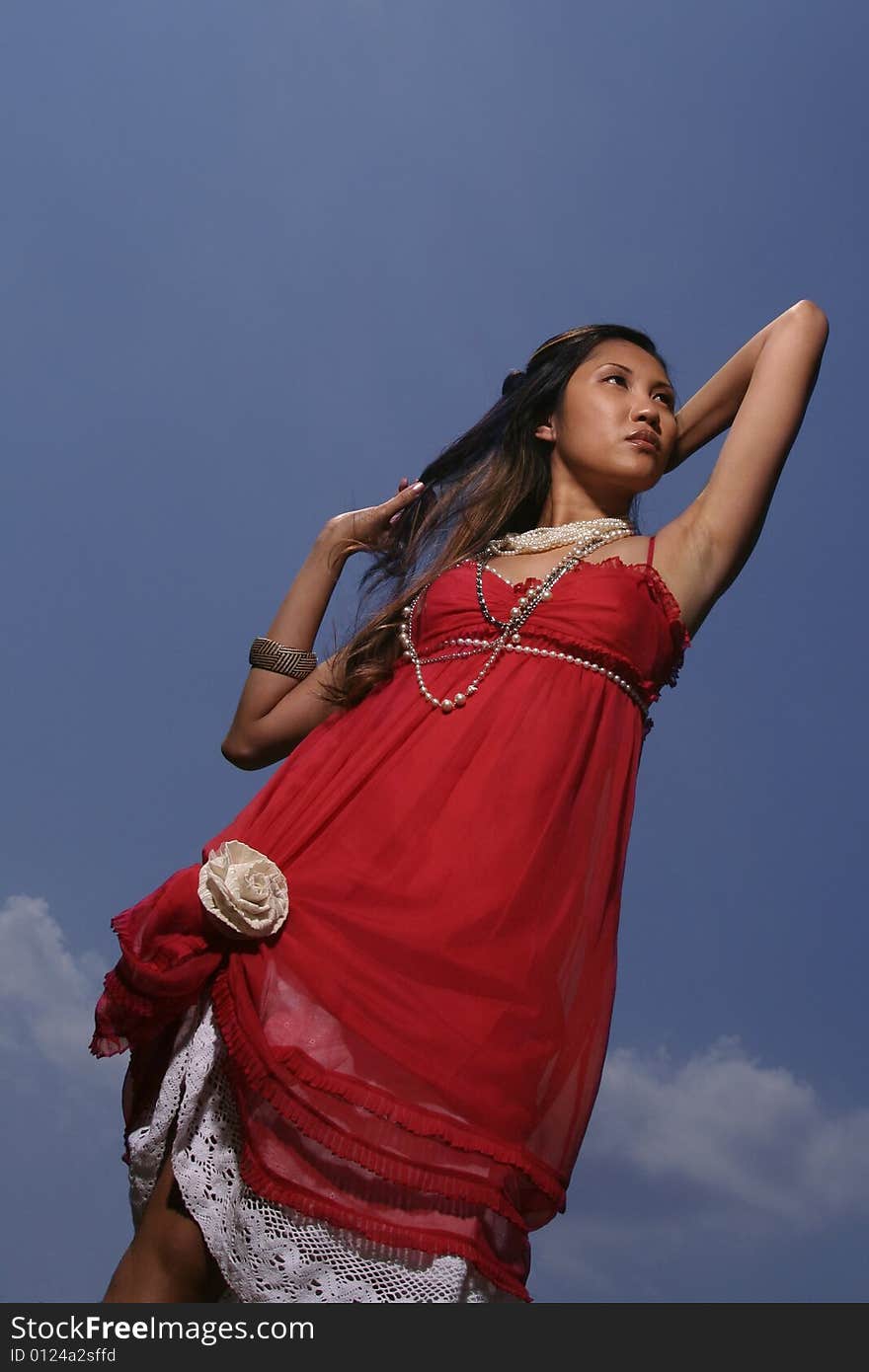 Filipino woman in red dress against blue sky. Filipino woman in red dress against blue sky