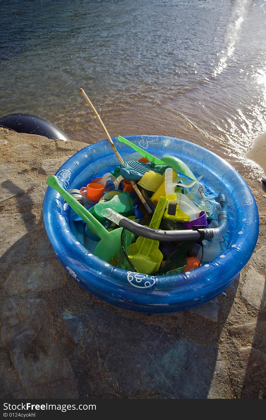 Beach toys collected in a blue plastic paddling pool at the end of the afternoon on the beach at Tamariu, Costa Brava, Catalonia, Spain. Beach toys collected in a blue plastic paddling pool at the end of the afternoon on the beach at Tamariu, Costa Brava, Catalonia, Spain