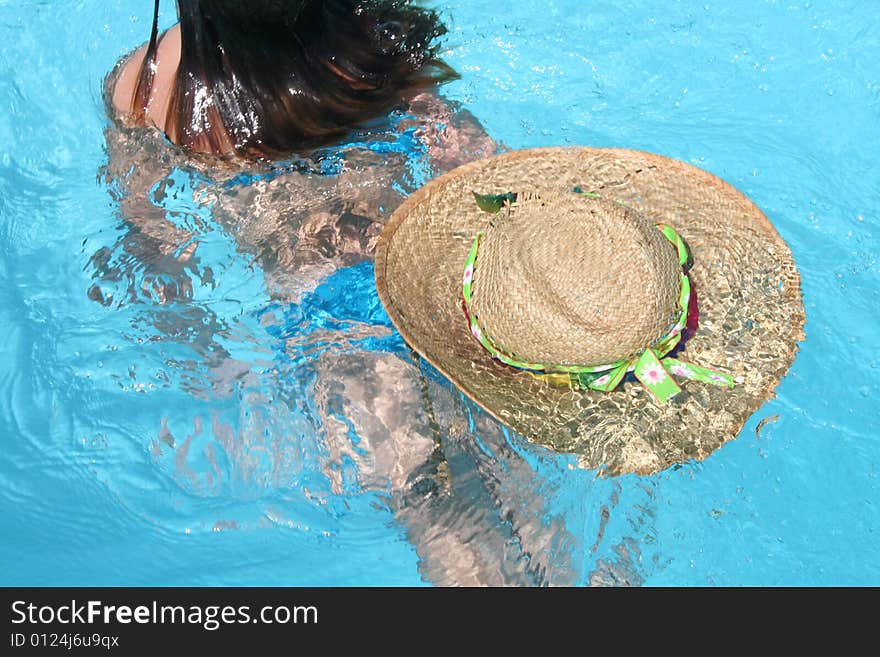 Girl swimming away with straw hat floating behind. Girl swimming away with straw hat floating behind.