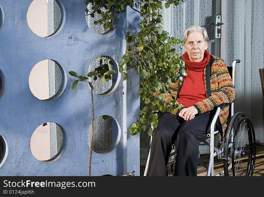 An elderly woman is sitting in a wheelchair in a garden.  She is looking at the camera.  Horizontally framed shot. An elderly woman is sitting in a wheelchair in a garden.  She is looking at the camera.  Horizontally framed shot.