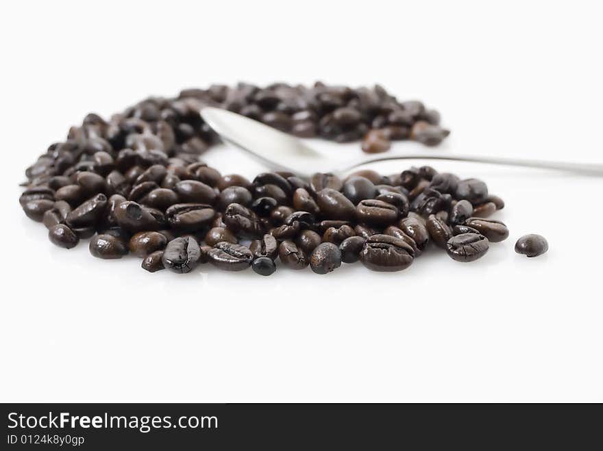 Closeup shot of coffee beans against white background with teaspoon