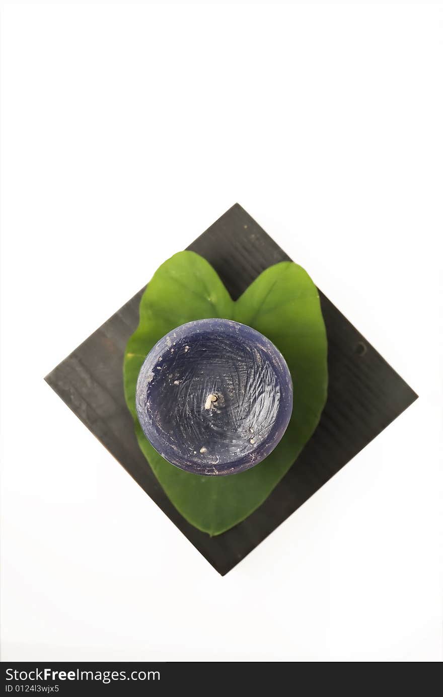 Still life of candle, leaf, and wooden candlestand against white background. Still life of candle, leaf, and wooden candlestand against white background