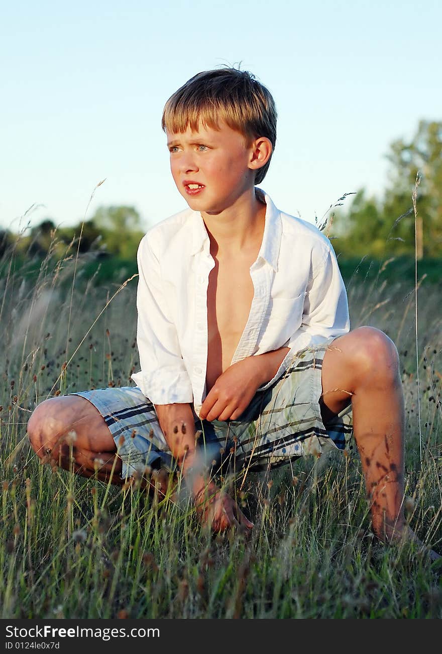 Boy Sitting in Field of Grass - Vertical