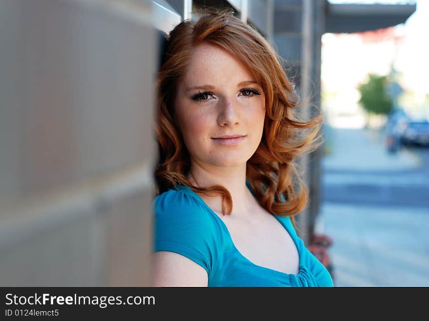 A young girl is standing with her back to a wall of bricks.  She is smiling at the camera.  Horizontally framed shot. A young girl is standing with her back to a wall of bricks.  She is smiling at the camera.  Horizontally framed shot.