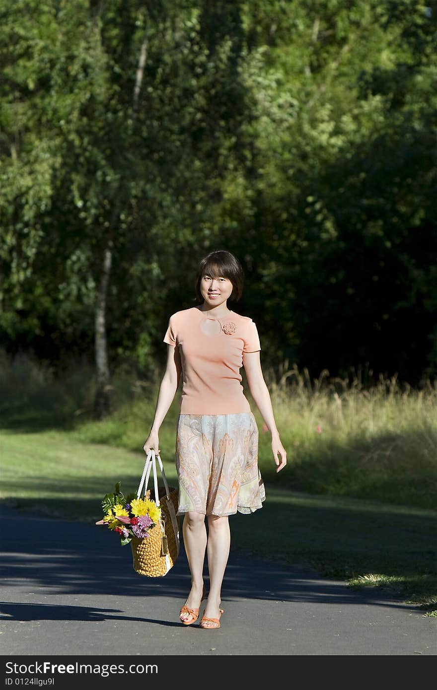 Woman Walks Carrying Flowers - Vertical