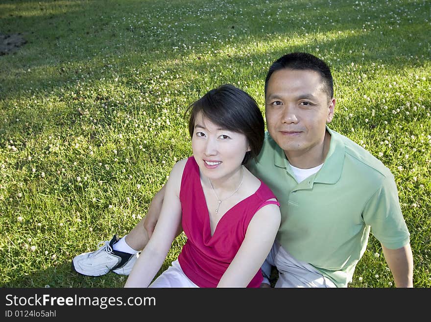 Smiling Couple Sitting on Grass - Horizontal