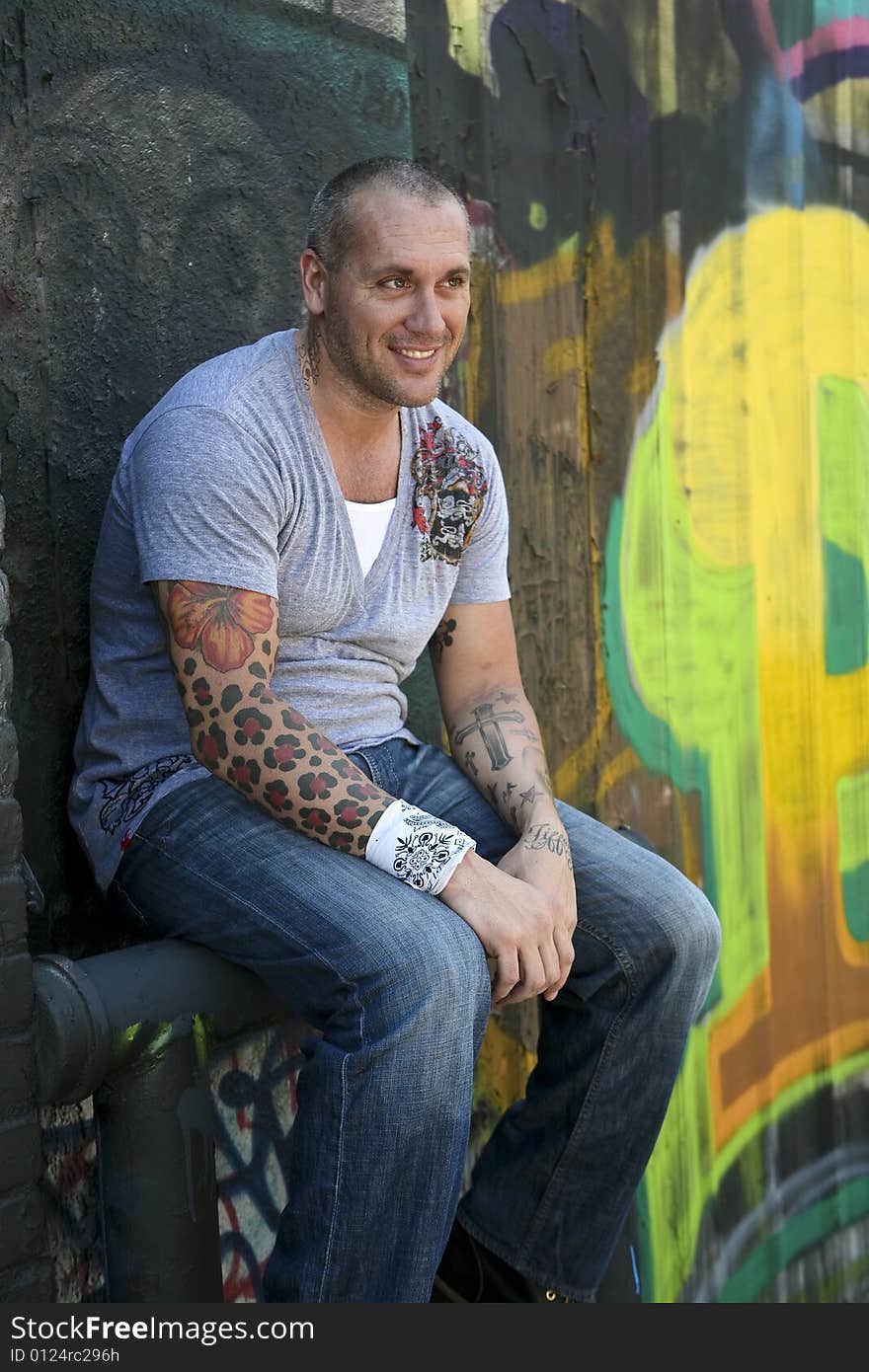 Handsome Male Fashion model posing by graffiti covered wall