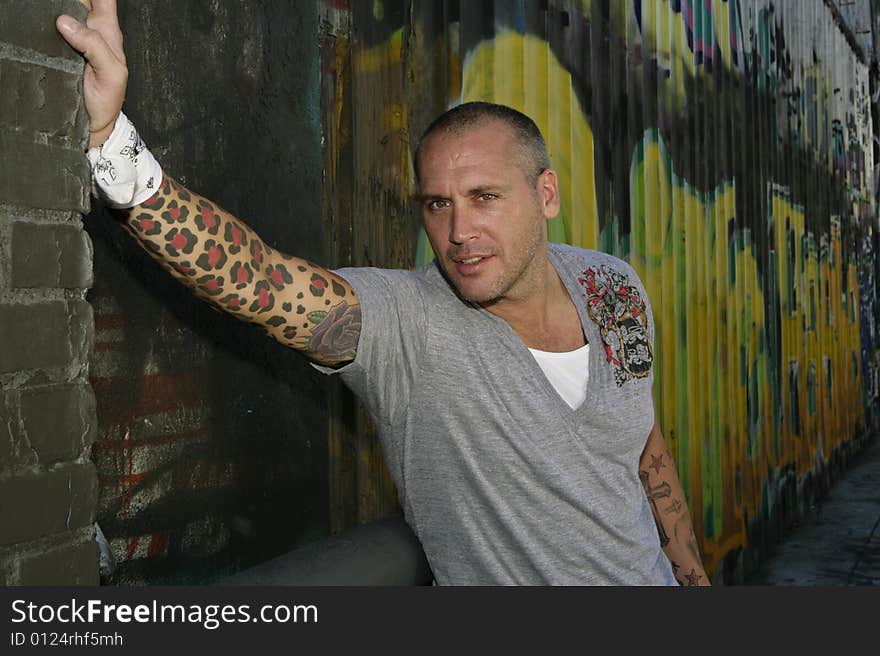 Handsome Male Fashion model posing by graffiti covered wall