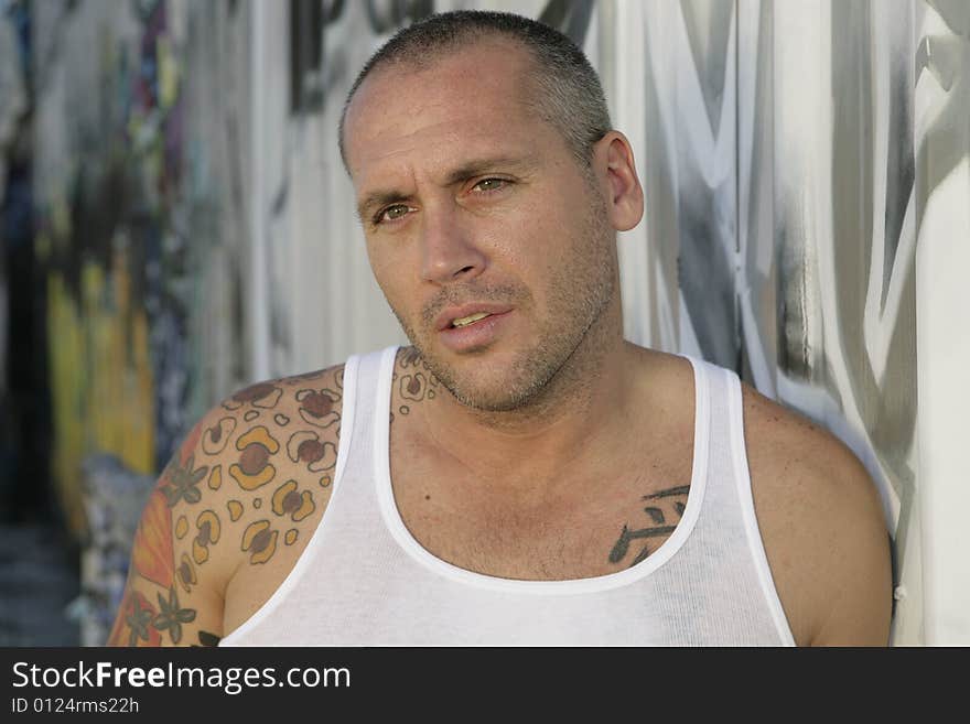 Handsome Male Fashion model posing by graffiti covered wall