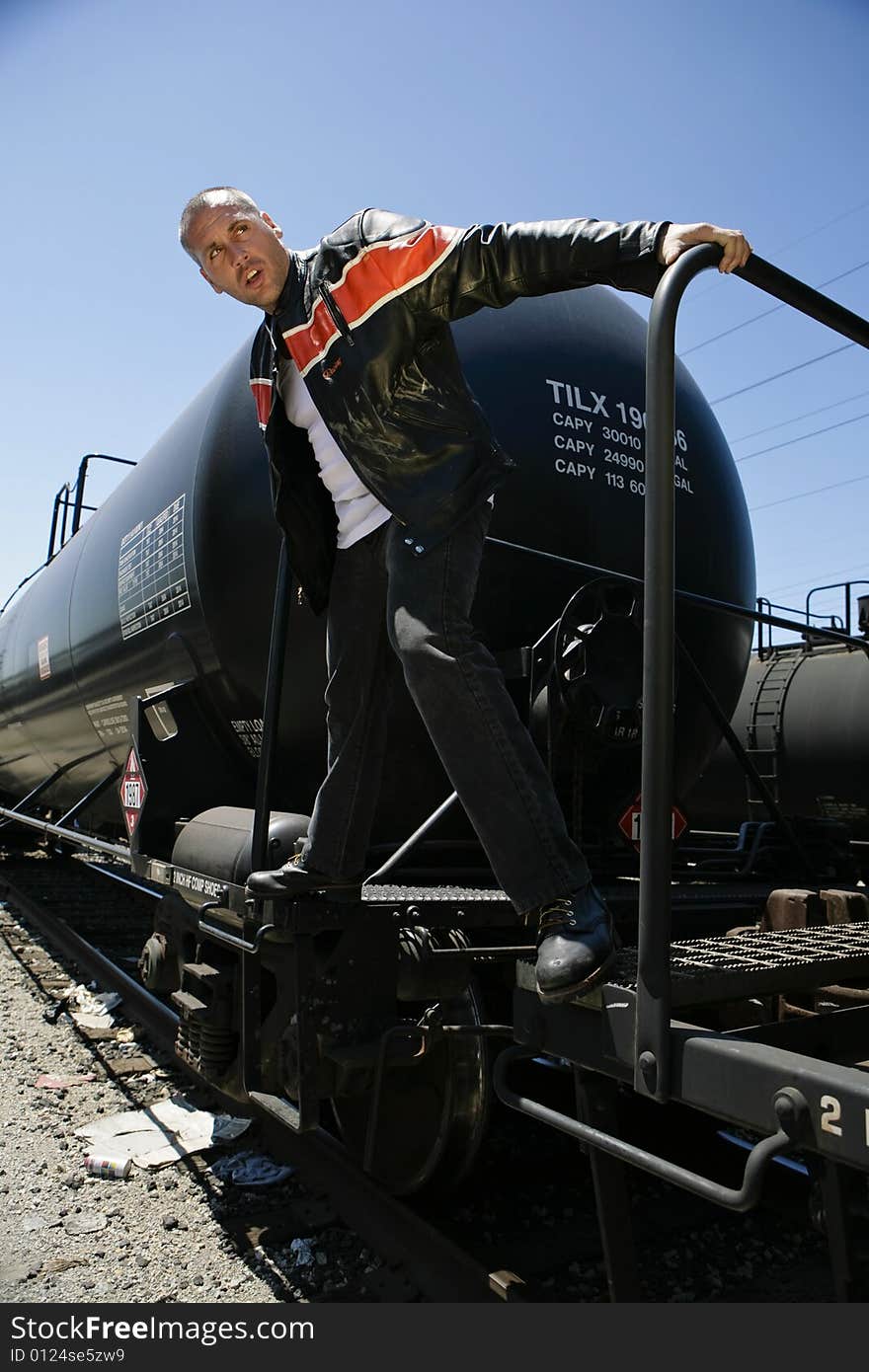 Male fashion model posing outdoors on a train. Male fashion model posing outdoors on a train