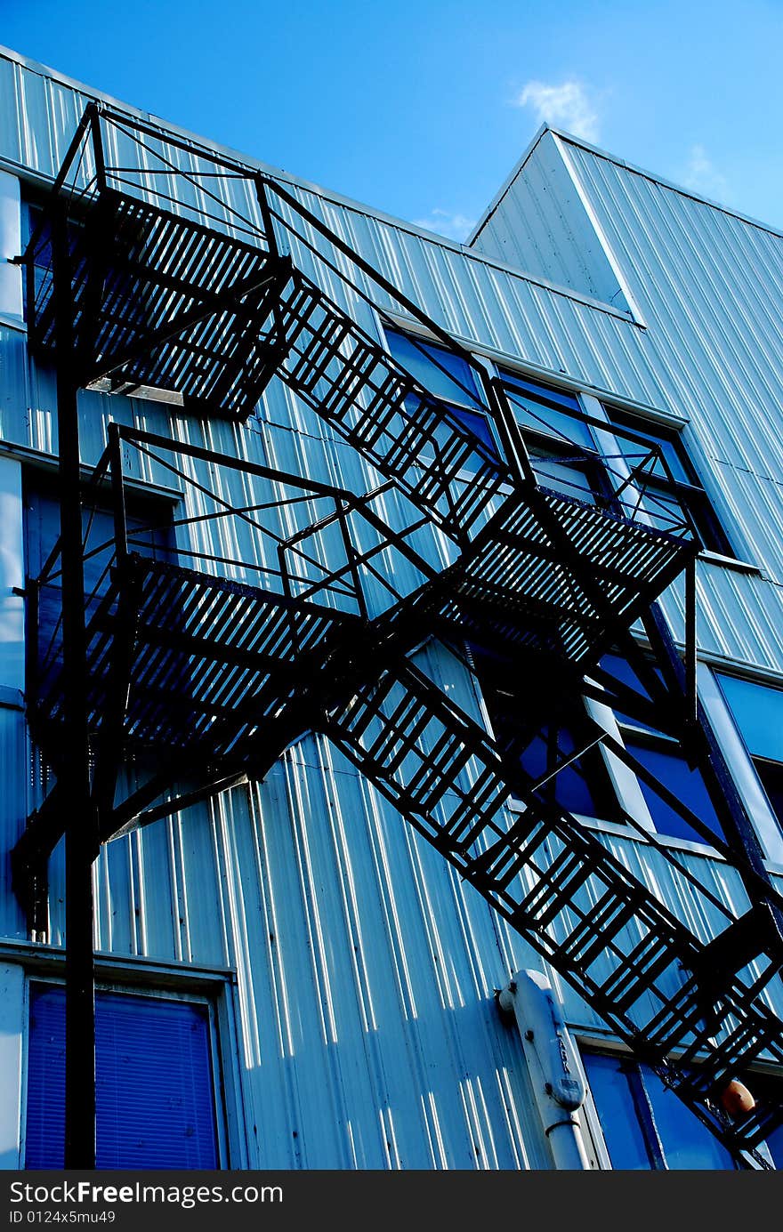 Stairs on the outside of a tin building zig zagging down to the ground. Stairs on the outside of a tin building zig zagging down to the ground