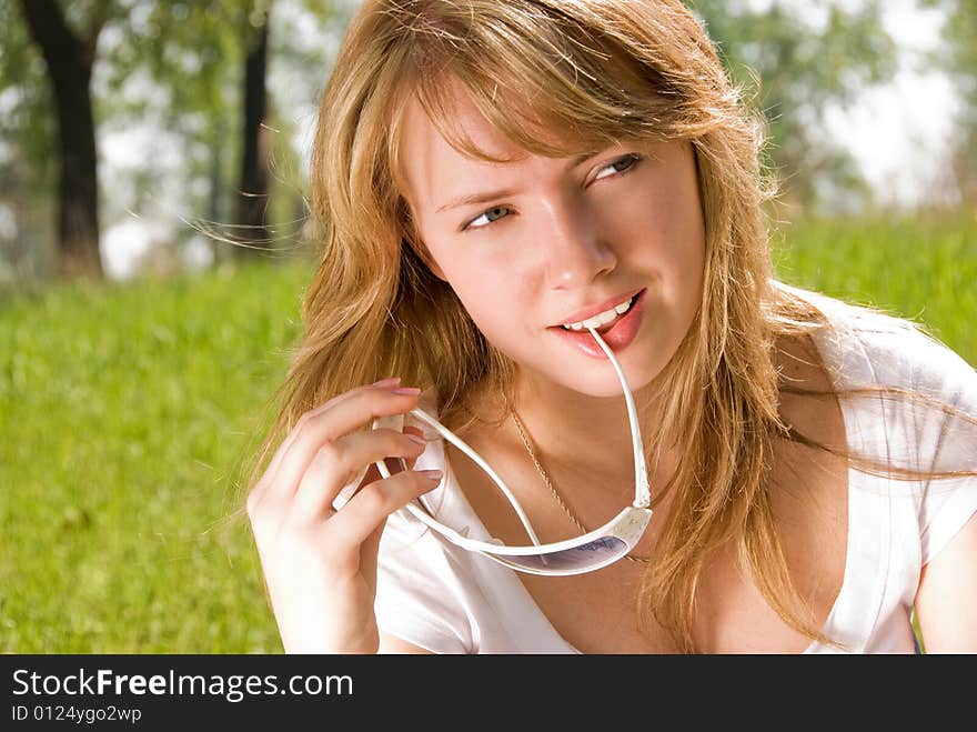 Thoughtful blond girl sitting on the grass in the park. Thoughtful blond girl sitting on the grass in the park