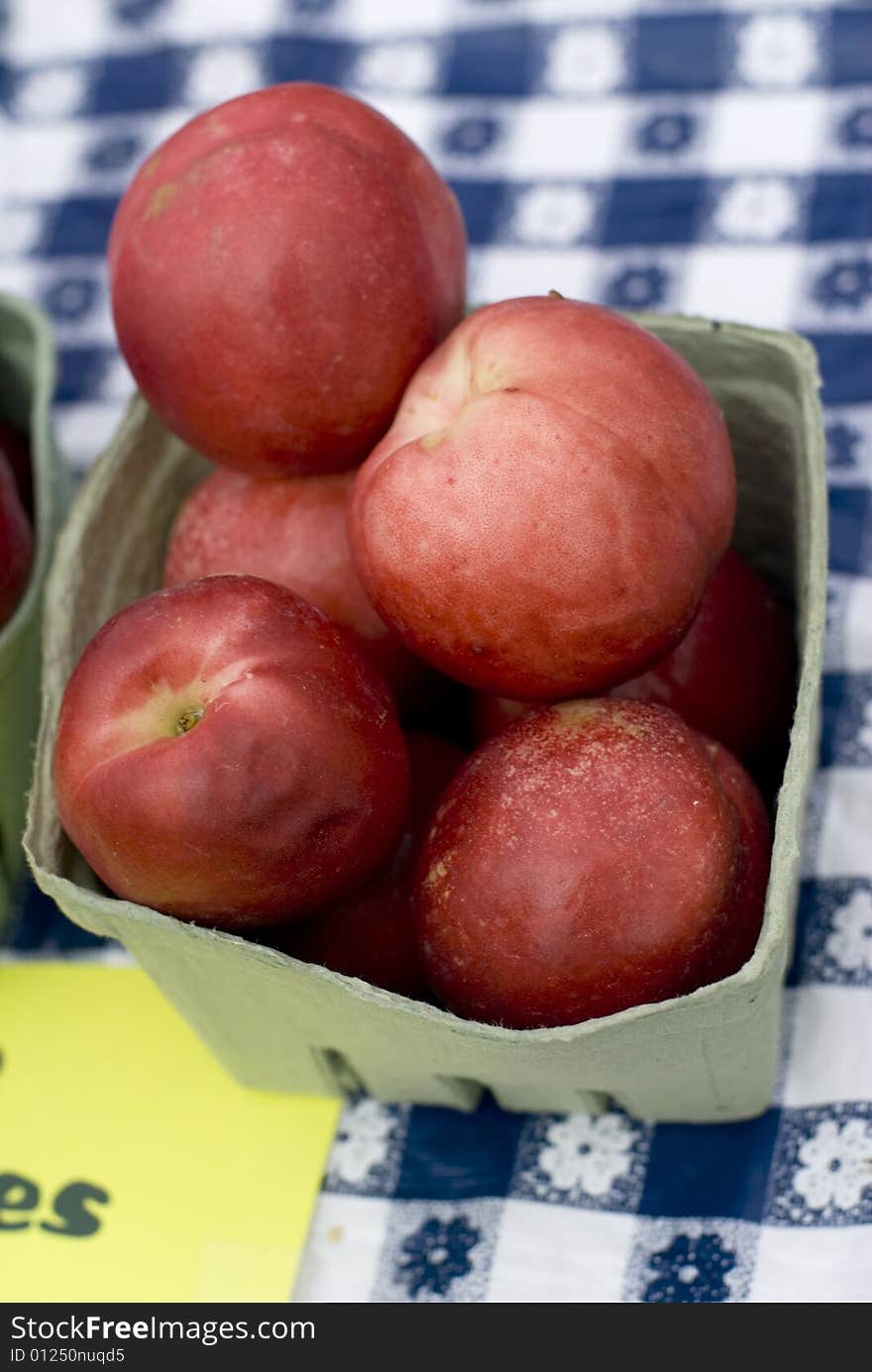 Sweet nectarines displayed on a white and blue checked cloth. Sweet nectarines displayed on a white and blue checked cloth.