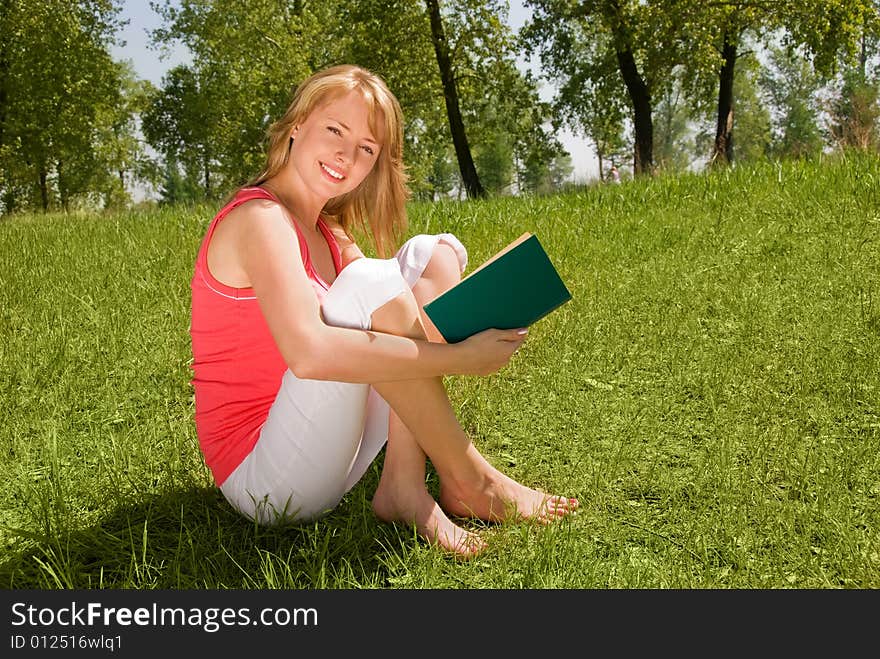 Pretty young girl reading a book outdoor