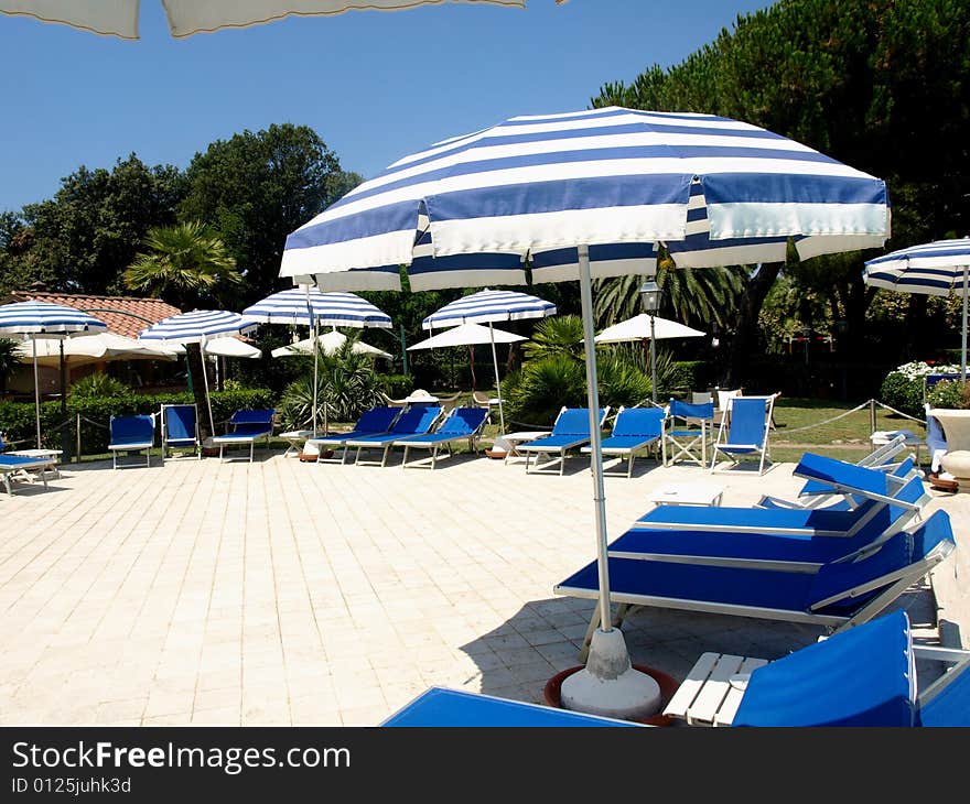 A beautiful shot of beach umbrellas and deck chairs in a solarium near a pool. A beautiful shot of beach umbrellas and deck chairs in a solarium near a pool