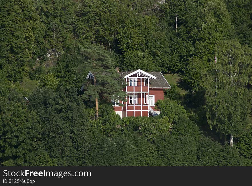 Old, traditional style red house among the trees in a green forest. Old, traditional style red house among the trees in a green forest.