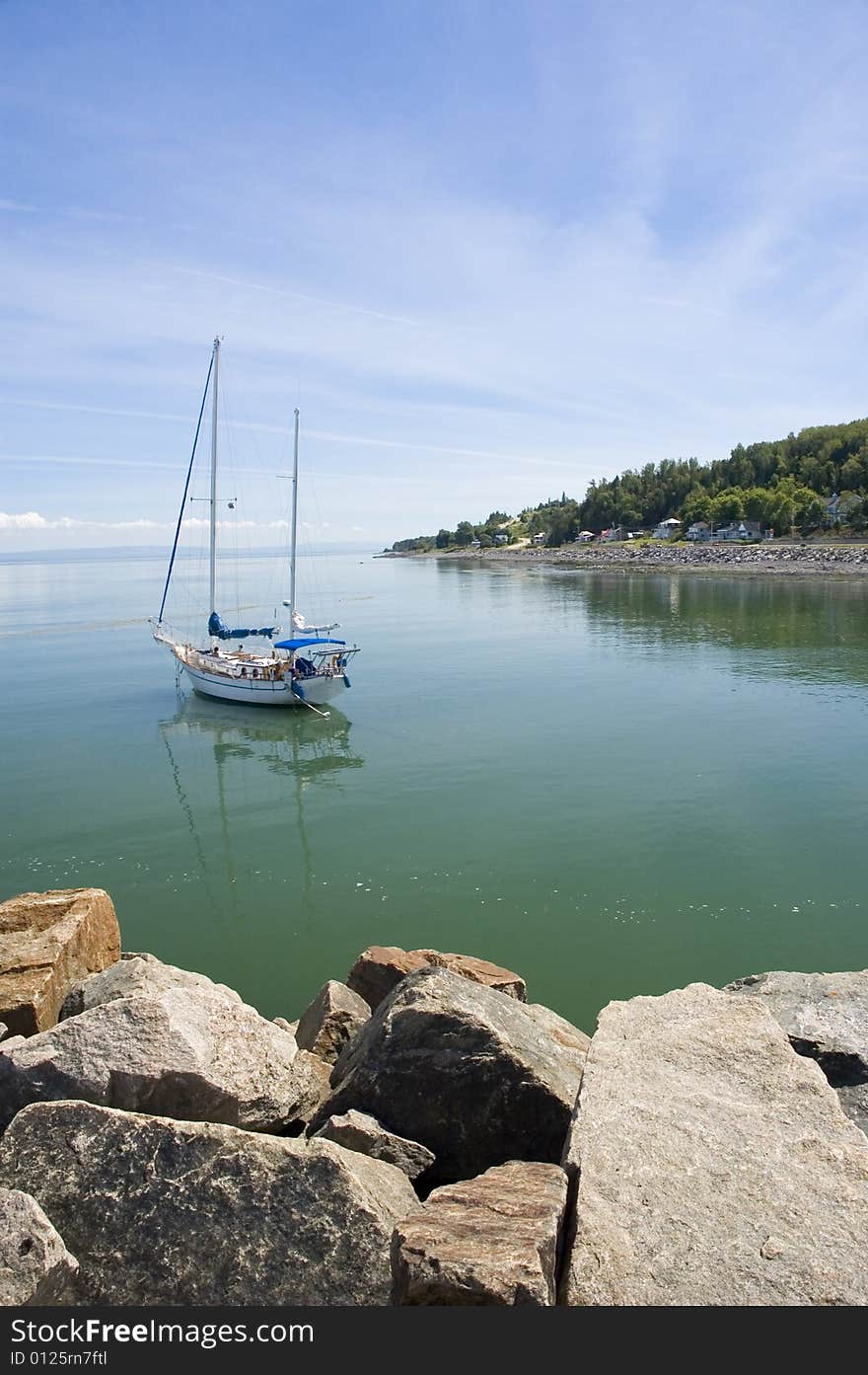 Sail boat on a calm river surrounded by a mountain