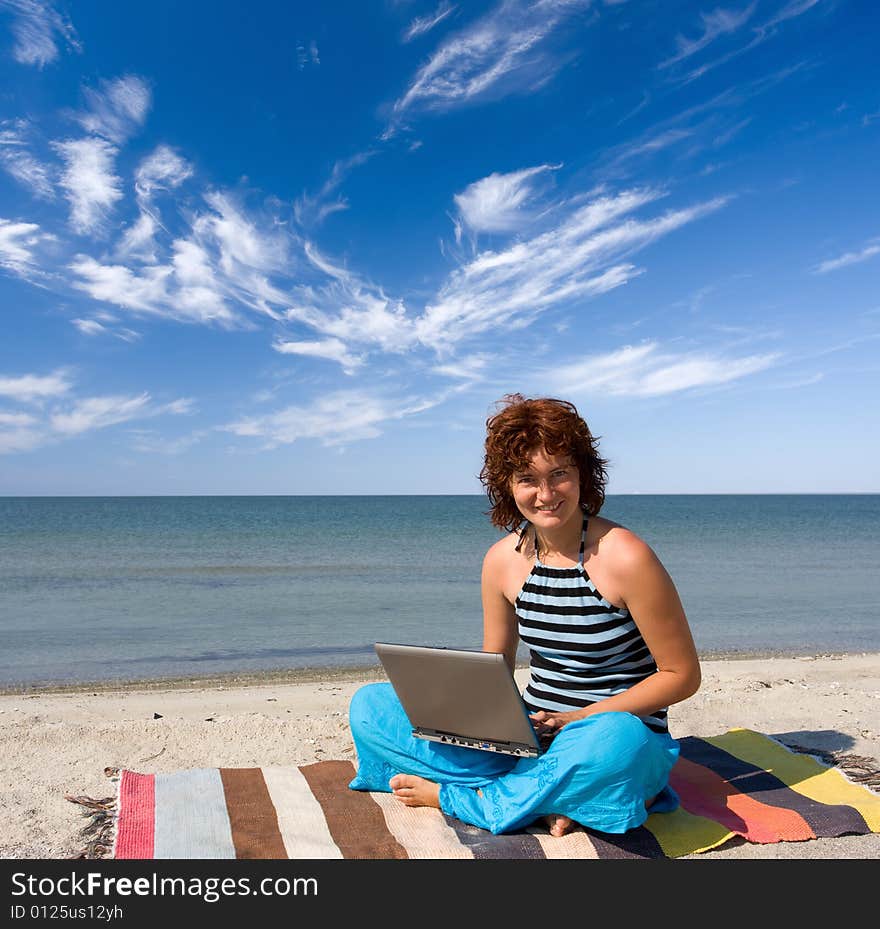 Girl sitting with laptop on the sea coast. Girl sitting with laptop on the sea coast