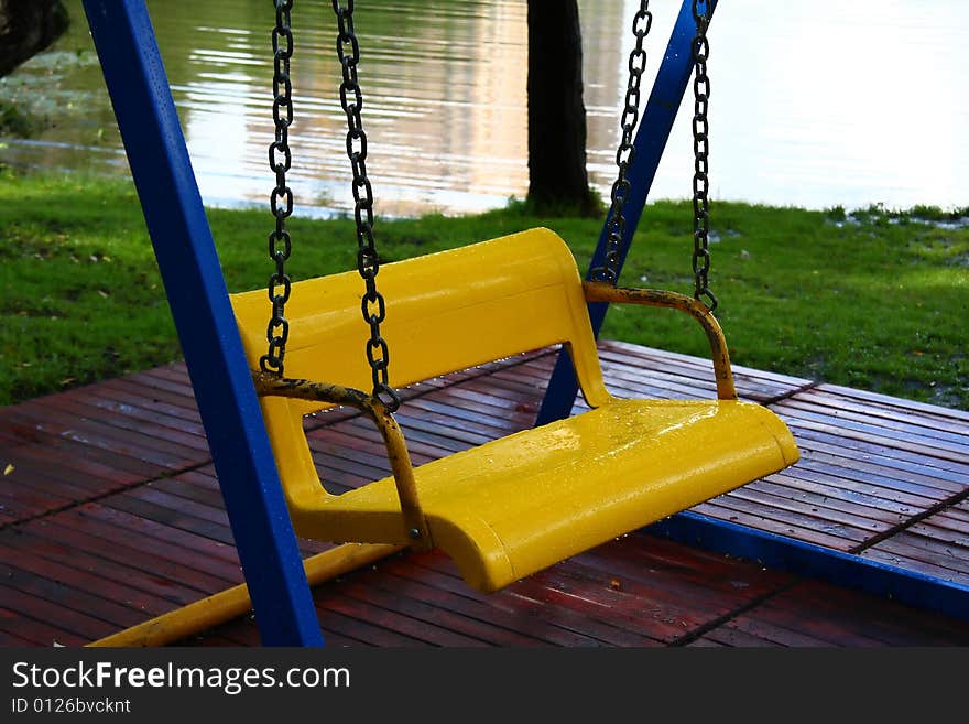 Bright yellow-blue children's swings in the park. Bright yellow-blue children's swings in the park