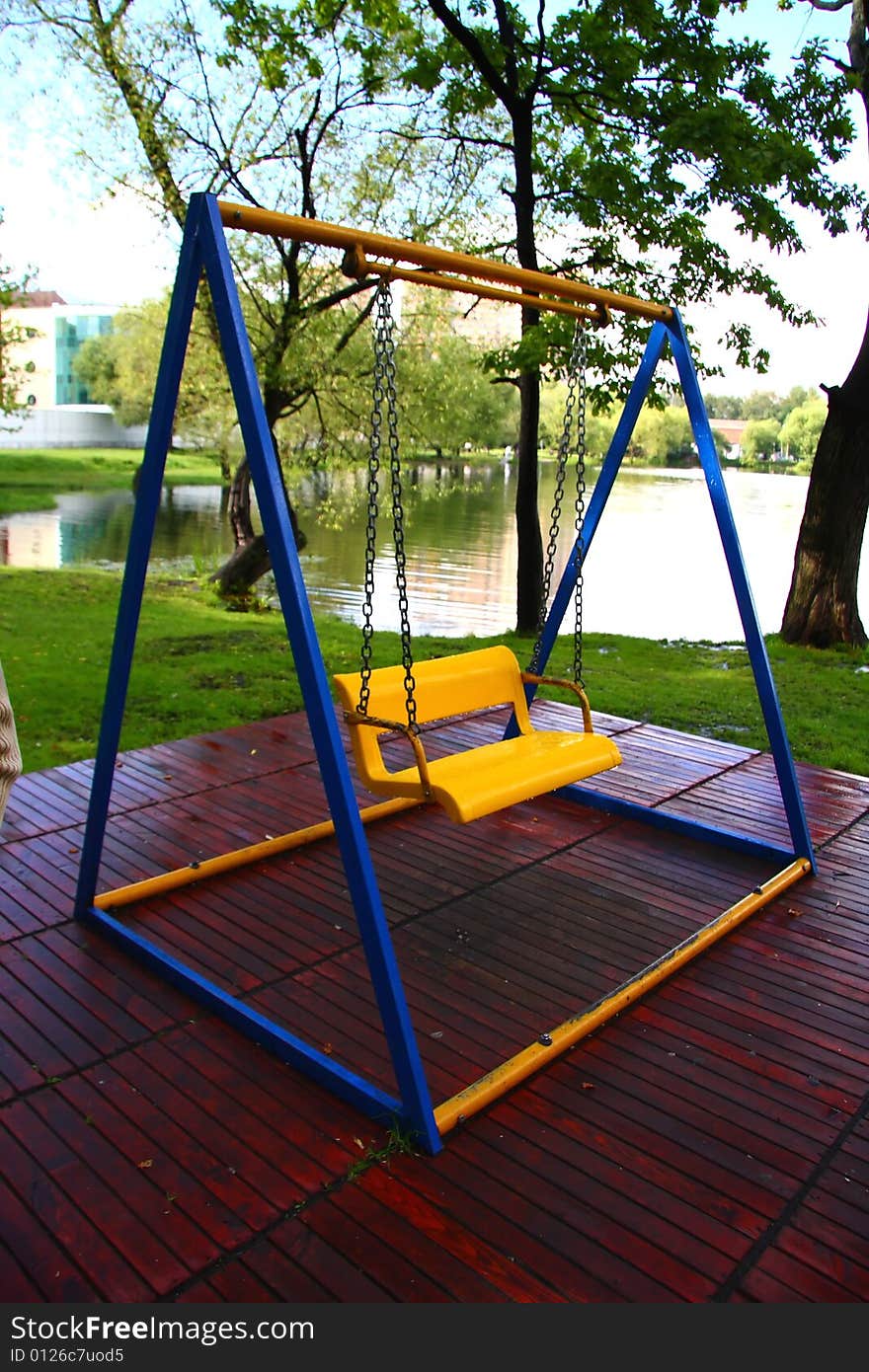 Bright yellow-blue children's swings in the park. Bright yellow-blue children's swings in the park