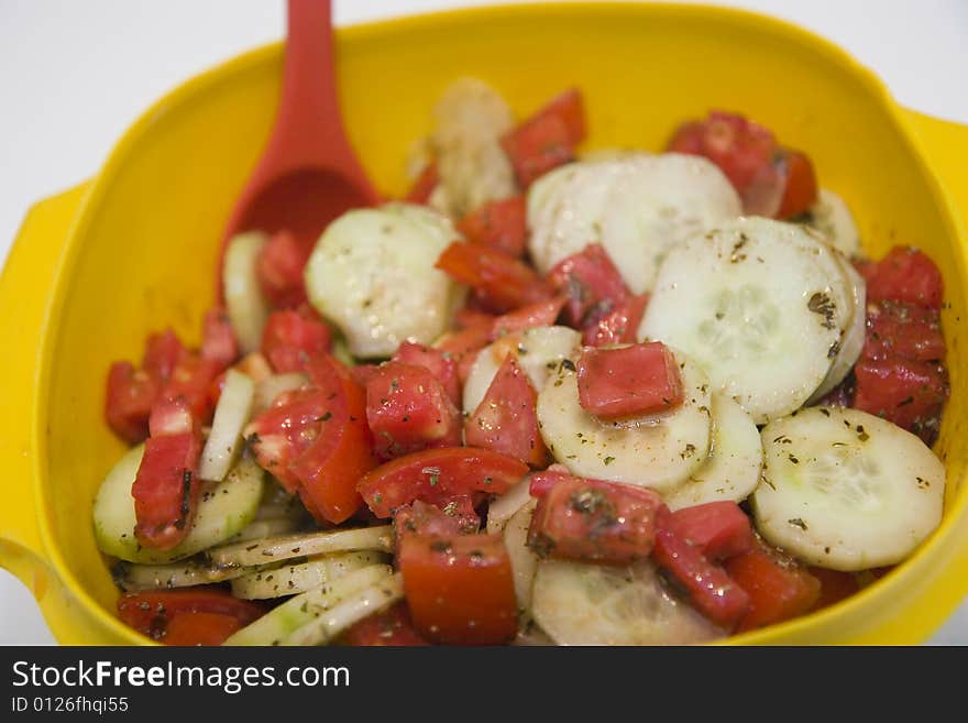 Cucumber and Tomato Salad in a yellow bowl with red spoon