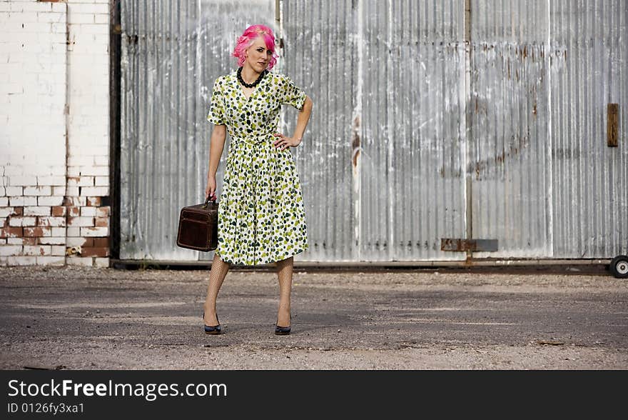 Woman with pink hair in an alley with small suitcase. Woman with pink hair in an alley with small suitcase