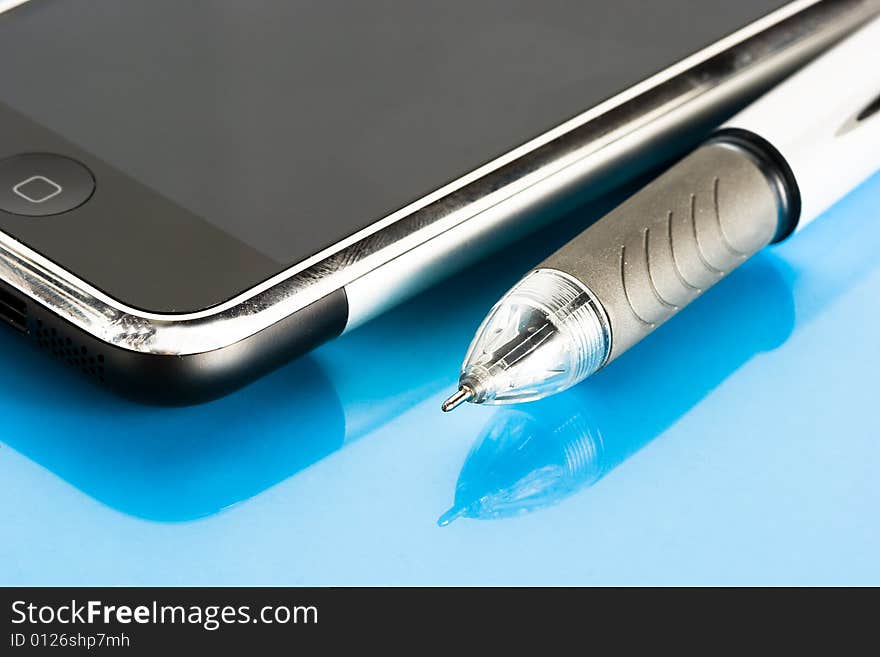 Pen and mobile phone on blue background