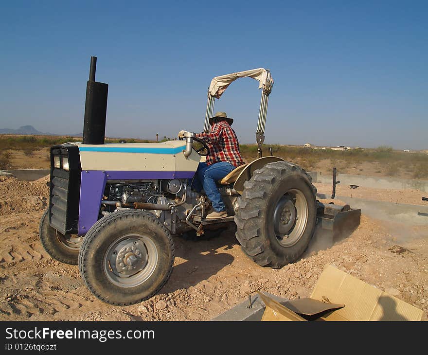 Man on tractor looking backwards as he works. Horizontally framed shot. Man on tractor looking backwards as he works. Horizontally framed shot.