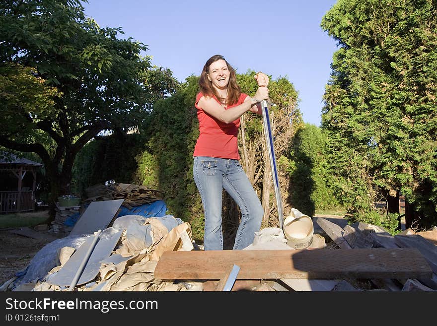 Woman laughing as she stands in a pile of rubble with a sword. Horizontally framed photograph. Woman laughing as she stands in a pile of rubble with a sword. Horizontally framed photograph