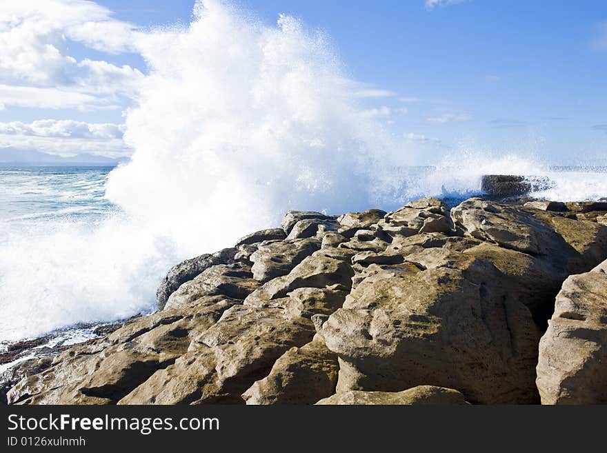 Powerful wave hammering a rocky shore resulting in a spectacular spray. Powerful wave hammering a rocky shore resulting in a spectacular spray.