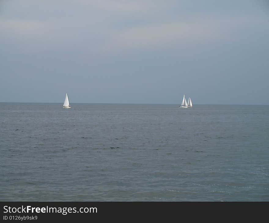 Three sail boats drift apart from one another. Three sail boats drift apart from one another.