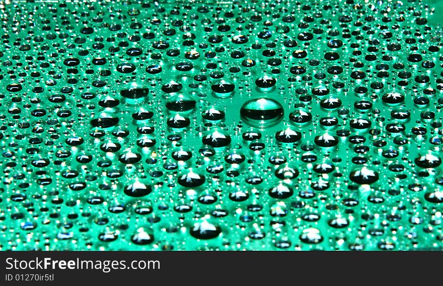 Drops of water on a green background in a view of the sun. Drops of water on a green background in a view of the sun