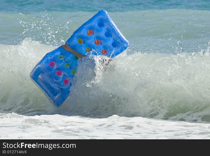 A person struggling with his lilo against a big wave. A person struggling with his lilo against a big wave.