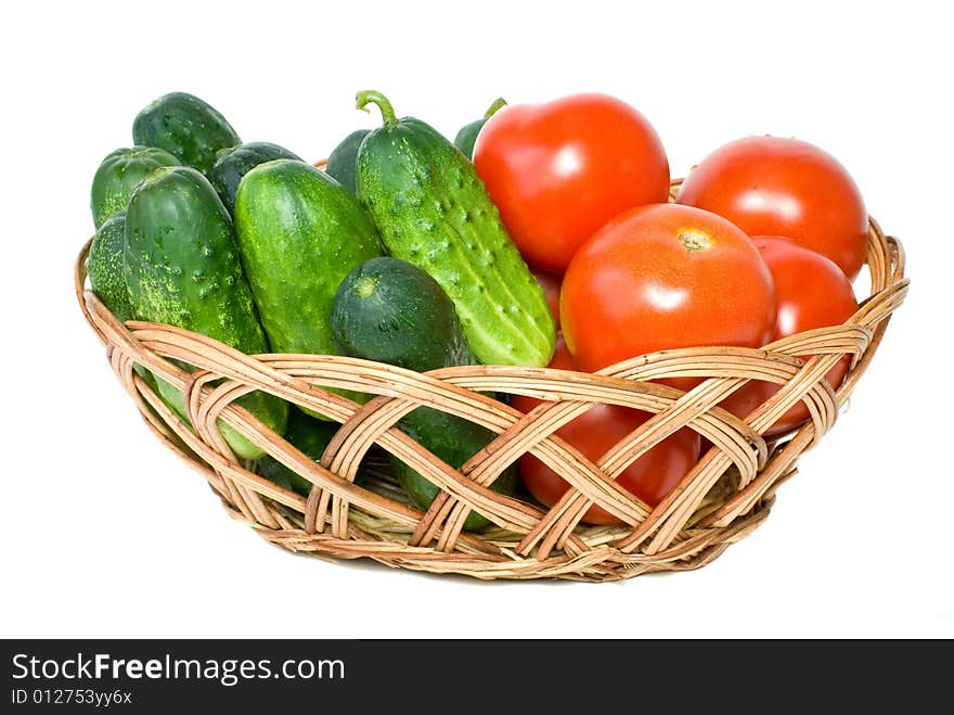 Wicker basket with some tomatoes and cucumbers isolated on the white background