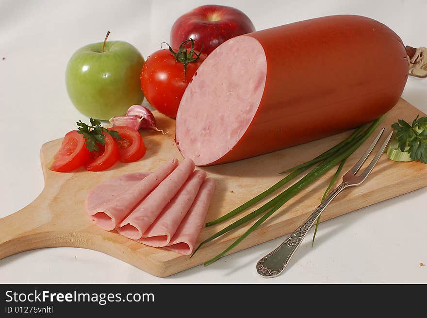 Ham in slices with vegetables on the bread board