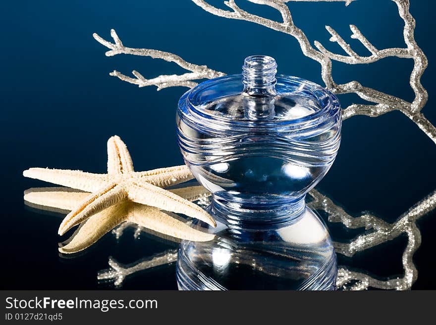 Blue bottle of perfume with starfish and corals