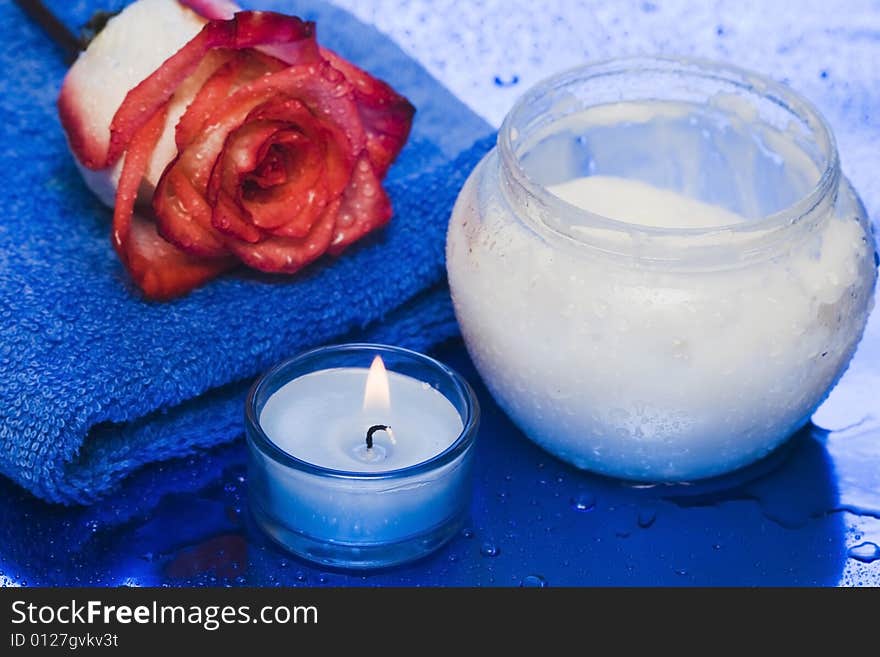 Cream, candle with rose on blue background