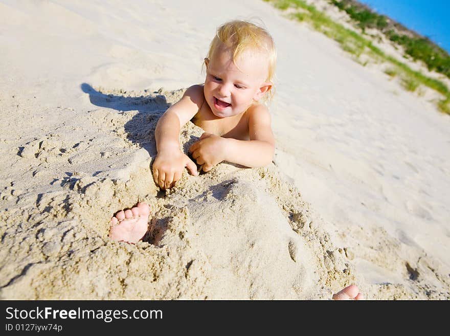 Young girl buried in the sand smiling at camera. Young girl buried in the sand smiling at camera