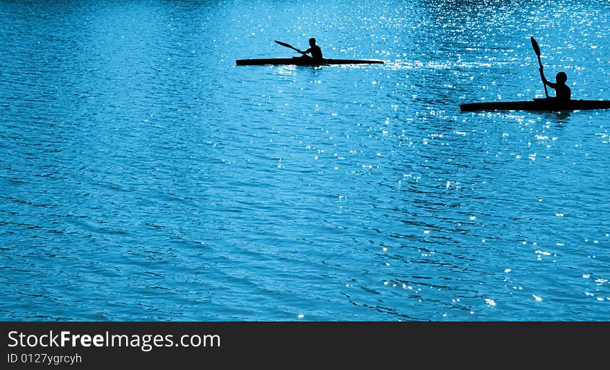 A black silhouettes of  child sportsmen on paddles (kayaks). A black silhouettes of  child sportsmen on paddles (kayaks)