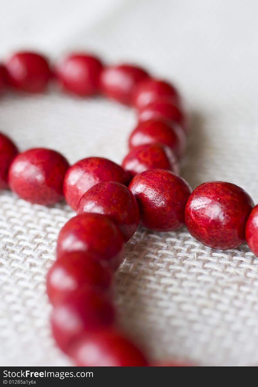 Red wooden beads are on a background from fabric