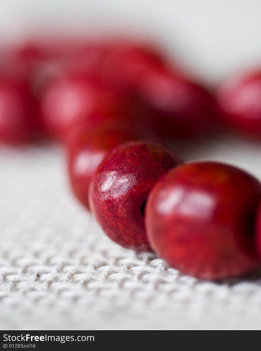 Red wooden beads are on a background from fabric