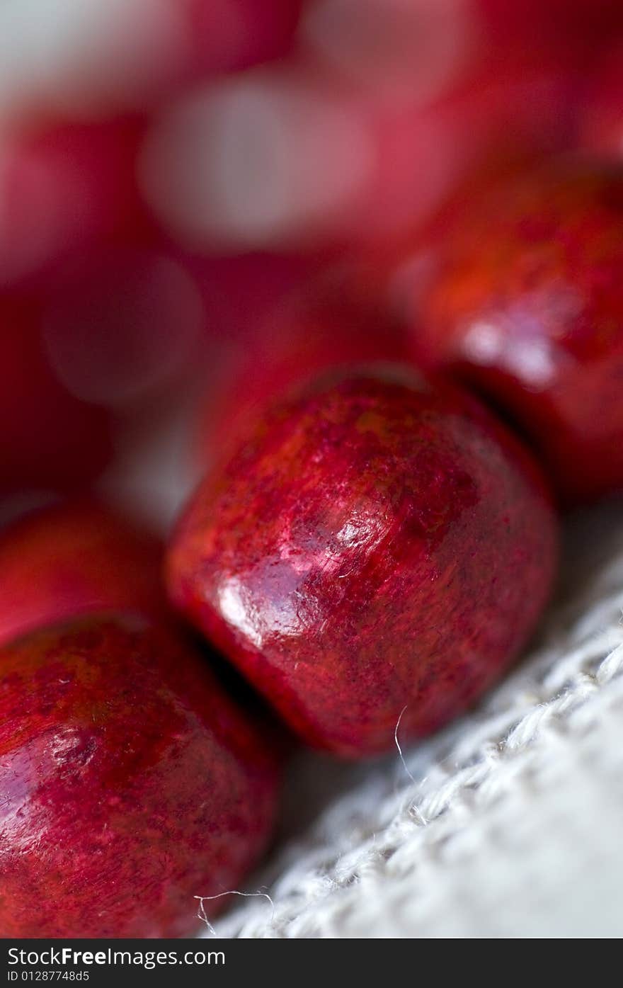 Red wooden beads are on a background from fabric - macro