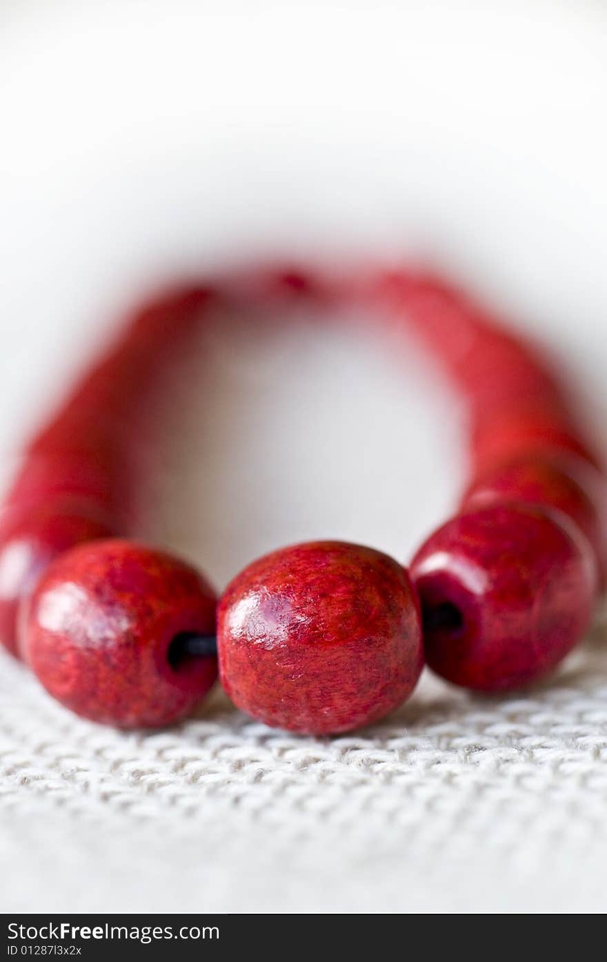 Red wooden beads are on a background from fabric - macro