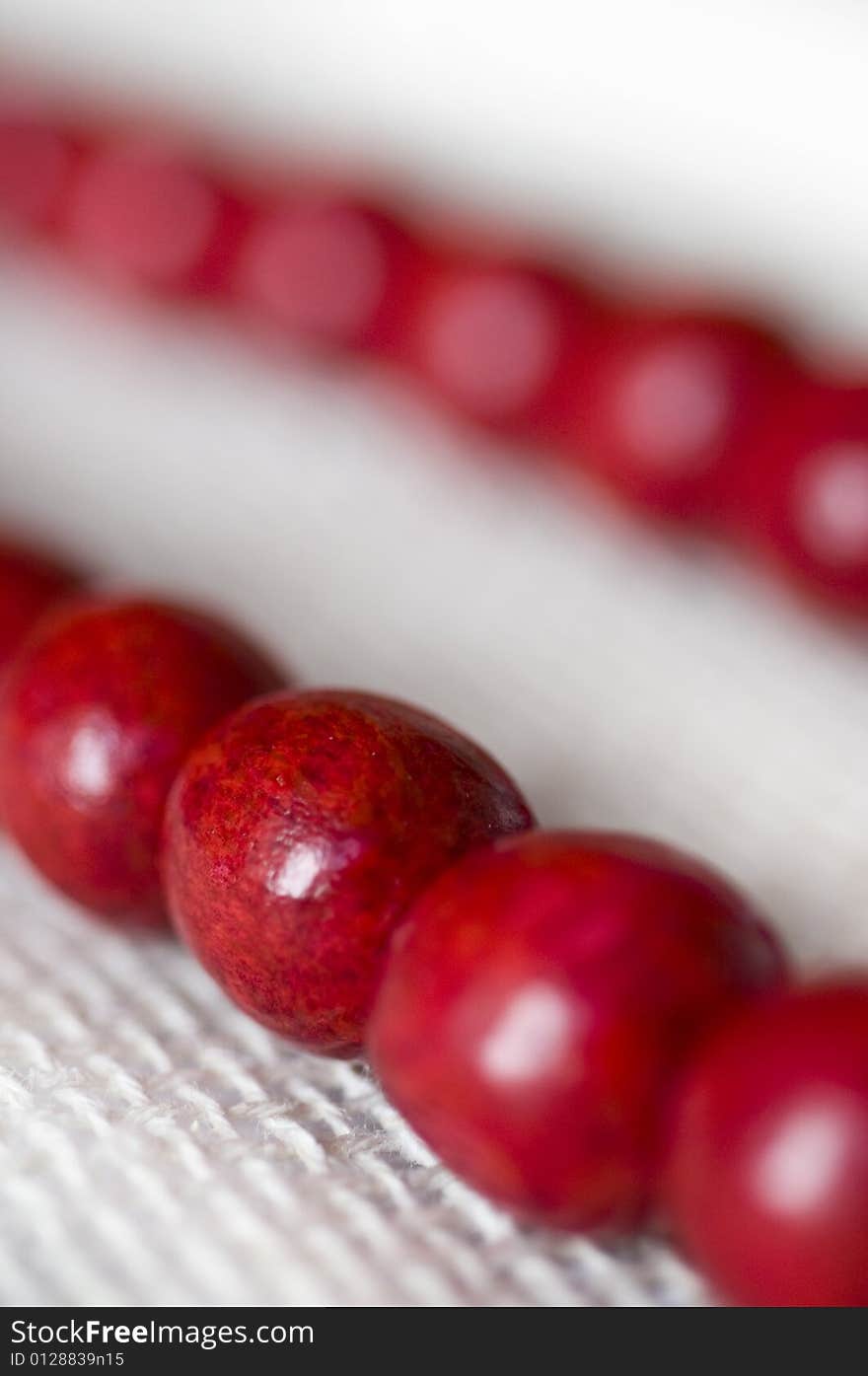 Red wooden beads are on a background from fabric - macro