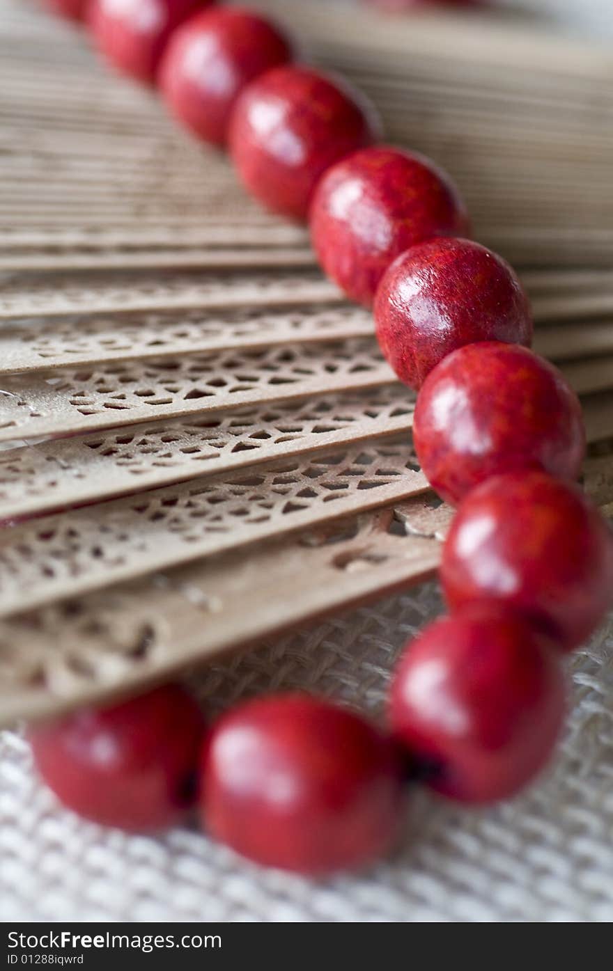 Red wooden beads on a wooden fan. Red wooden beads on a wooden fan