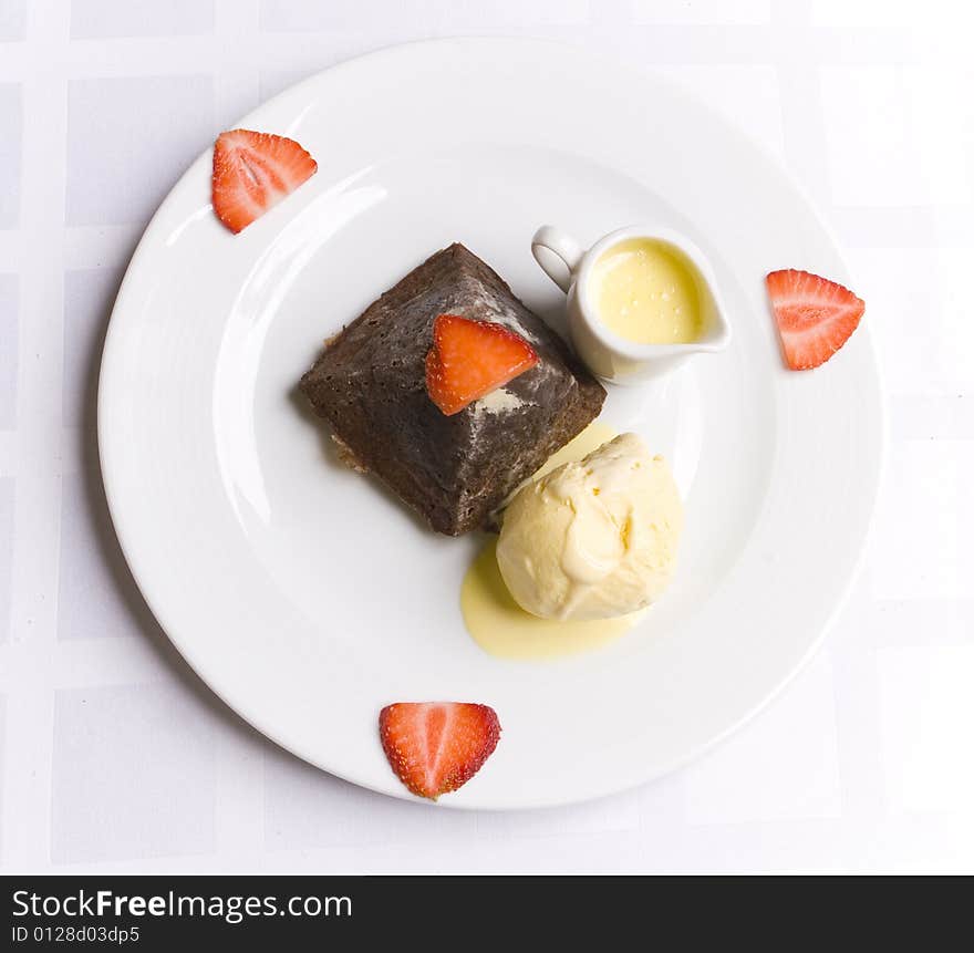 Chocolate dessert with strawberry, ice cream and milky sauce on white plate