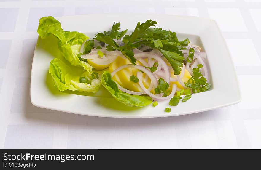 Herring with potatoes, onion and parsley on white plate