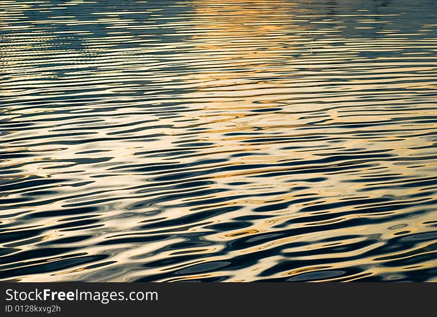 Warm golden tones of a sun reflected on the ripples of a sea surface. Warm golden tones of a sun reflected on the ripples of a sea surface